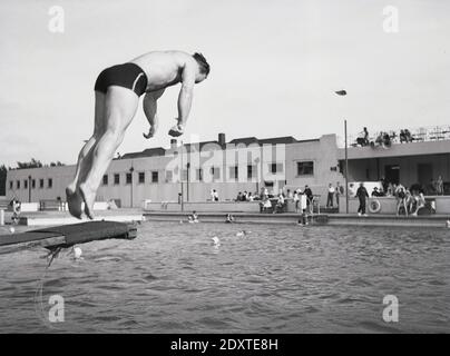 1950er Jahre, historisch, ein Mann auf einem Sprungbrett in einem Open Air Lido, Gravesend, Kent, England, Großbritannien, ich bin dabei, einen Tauchgang zu machen. Das große Schwimmbad mit Sprungbrettern wurde 1938 eröffnet und 1989 geschlossen. Stockfoto