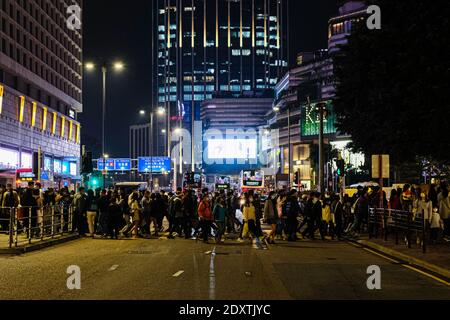 Hongkong, China. Dezember 2020. Menschen mit Schutzmaske und überqueren die Straße am Heiligabend. Trotz der Ankündigung von Regierungsbeschränkungen versammeln sich viele Menschen in Hongkong am Heiligabend, um zu feiern. Die Zahl der Todesopfer in Hongkong hat 135 erreicht, während die Zahl der bestätigten Fälle bei 8,424 liegt. Quelle: Keith Tsuji/ZUMA Wire/Alamy Live News Stockfoto