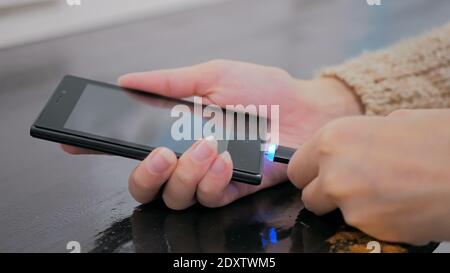 Woman's Hand stecken schwarze Blitz Ladekabel in Smartphone Stockfoto