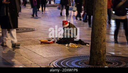 Alter Mann in Santa Claus bettelt auf der Avenue des Champs-Elysees in Paris, Frankreich Stockfoto