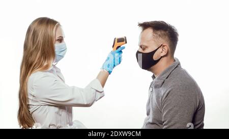 Überprüfung der Körpertemperatur des Patienten mit einem berührungslosen Thermometer, einer Krankenschwester, die eine medizinische Maske und blaue Einweghandschuhe trägt. Isoliert auf Weiß Stockfoto