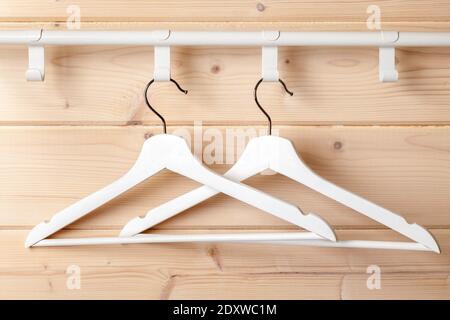 Zwei weiße Standard-Kleiderbügel hängen an der natürlichen Holzwand, Nahaufnahme Stockfoto