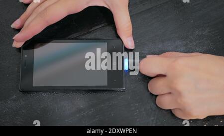 Woman's Hand stecken schwarze Blitz Ladekabel in Smartphone Stockfoto
