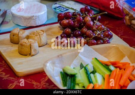 Eine Auswahl an Snacks, die auf einem Tisch serviert werden, darunter Crudites, rote Trauben, Käse und Schweinebraten. Stockfoto