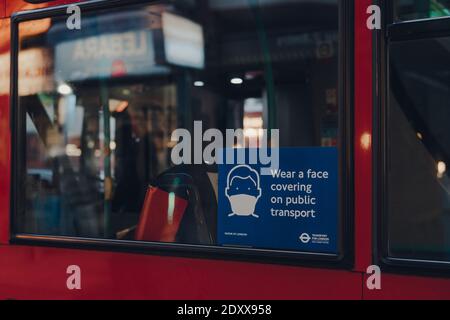 London, Großbritannien - 5. Dezember 2020: Tragen Sie ein Gesichtsmaskenschild auf dem Fenster eines roten Doppeldeckerbusses in London. Die Anforderungen wurden durch Coron eingeführt Stockfoto