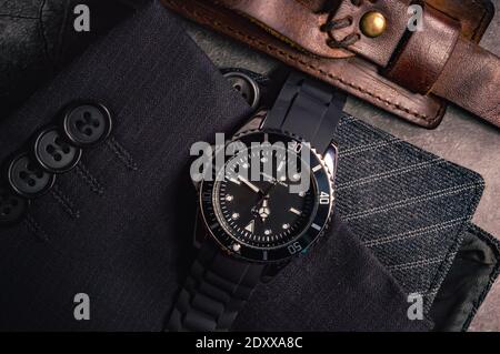 Nahaufnahme einer schwarzen Chrom-Herrenuhr auf einer Ärmel mit Knöpfen und Lederarmband Stockfoto