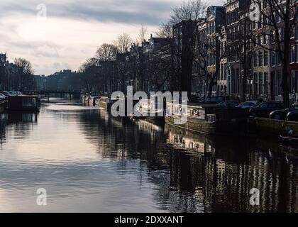 Amsterdam, Niederlande 16. Dezember 2020: Bild des Canal Korte Prinsengracht in Amsterdam mit Hausbooten, die in der späten Wintersonne glühen Stockfoto