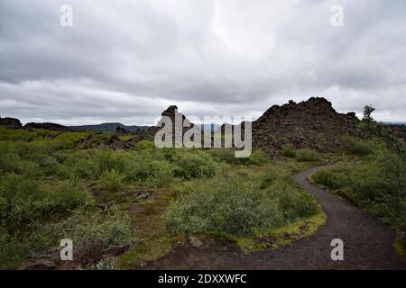 Ein Pfad schlängelt sich durch Dimmuborgir (Dunkle Burgen), ein großes Gebiet ungewöhnlich geformter Lavafelder östlich des Sees Mývatn in Nordisland. Stockfoto