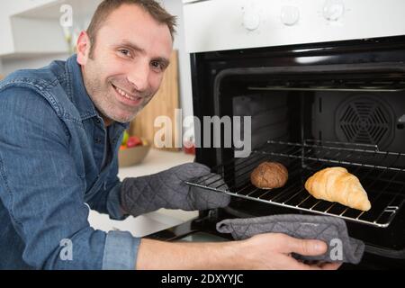 Mann backen Croissants im Ofen zu Hause Stockfoto