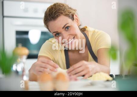 Eine Frau, die den Teig auf einem Holztisch knetet Stockfoto