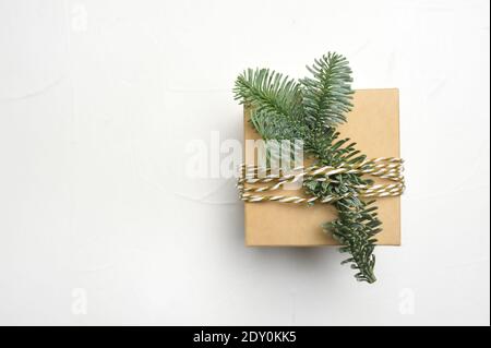 Weihnachtskomposition mit grünen Tannenzweigen und Kraft Geschenkbox Auf weißem Holzhintergrund mit Copyspace Stockfoto