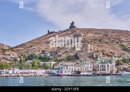 Sewastopol, Russland - 6. Oktober 2020: Blick auf den Stadtstrand Balaklava und den Berg Krepostnaya mit den Ruinen der mittelalterlichen genuesischen Festung Chembalo, Stockfoto