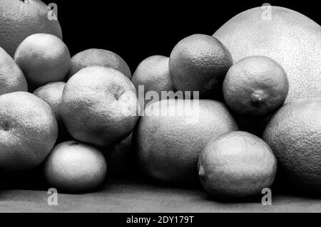Monochrome isolierte orange und grüne Farbgruppen Zitrusfrüchte auf schwarzem Hintergrund. Orangen, Mandarinen, Limetten, Pomelo, Grapefruits auf blauem Tischl Stockfoto
