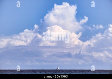 Seascape mit kleinem Segelboot unter großen Wolken Stockfoto