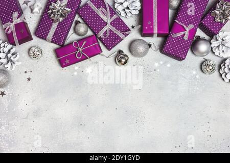 Weihnachten oder Winter Komposition. Weihnachtsgeschenke, Ornamente und Konfetti auf grauem Steingrund. Flach liegend, Draufsicht, Kopierbereich. Stockfoto