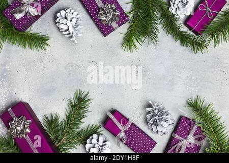 Weihnachten oder Winter Komposition. Weihnachtsgeschenke, Tannenzweige und Ornamente auf grauem Steingrund. Flach liegend, Draufsicht, Kopierbereich. Stockfoto