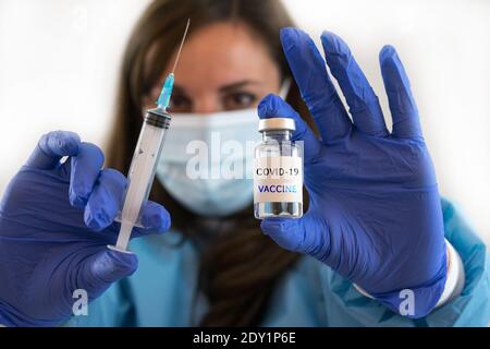 Kaukasische Frau Arzt oder Krankenschwester in Uniform und Handschuhe Tragen Gesichtsmaske Schutz in Labor halten Nadel Spritze Medikament Und Medizin Fläschchen Impfstoff bo Stockfoto