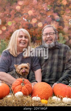 Glückliches älteres Baby Boomer Paar posiert in einer Herbstszene Mit Hund und Pumkins Stockfoto