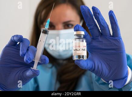 Kaukasische Frau Arzt oder Krankenschwester in Uniform und Handschuhe Tragen Gesichtsmaske Schutz in Labor halten Nadel Spritze Medikament Und Medizin Fläschchen Impfstoff bo Stockfoto