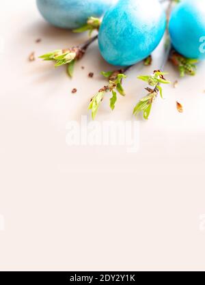 Drei blaue Ostereier und Frühlingszweige mit grünen Blättern auf einem weißen Tisch Stockfoto