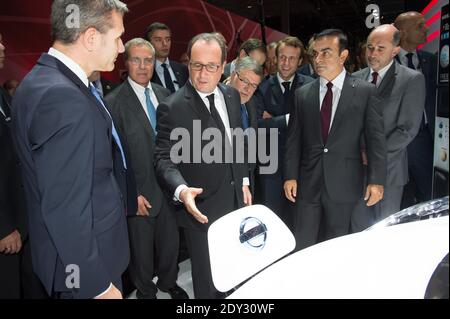 Der französische Präsident Francois Hollande (C) stopft ein elektrisches Nissan-Auto an, während er mit dem CEO von Nissan-Renault Carlos Ghosn (3-R) während eines offiziellen Besuchs auf dem Pariser Automobilsalon "Mondial de l'Automobile" in Paris, Frankreich, am 03. Oktober 2014, den Nissan-Stand besucht. Der Pariser Automobilsalon, der alle zwei Jahre stattfindet, findet vom 04. Bis 19. Oktober 2014 statt. Internationale Automobilhersteller präsentieren ihre neuesten Modelle und Studien Foto von Villard/Pool/ABACAPRESS.COM Stockfoto