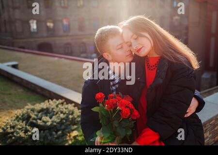 Valentinstag Datum. Mann umarmt Freundin hält Strauß von roten Rosen im Freien. Romantisches Paar in der Liebe Stockfoto