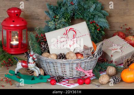 weihnachtsdekoration mit Geschenkbox, Äpfeln, Walnüssen und Mandarinen im Korb Stockfoto