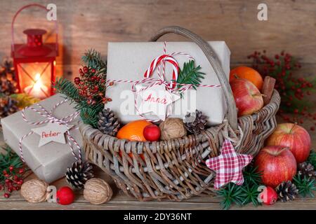 weihnachtsdekoration mit Geschenkbox, Äpfeln, Walnüssen und Mandarinen im Korb Stockfoto