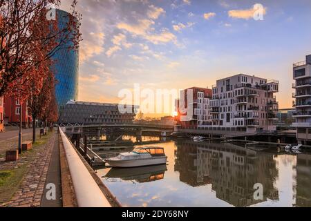 Westhafen mit Kanal vom Main in Frankfurt am Morgen mit Sonnenaufgang und Wolken im Wohngebiet. Blauer Himmel zwischen Gebäuden und Fluss Stockfoto