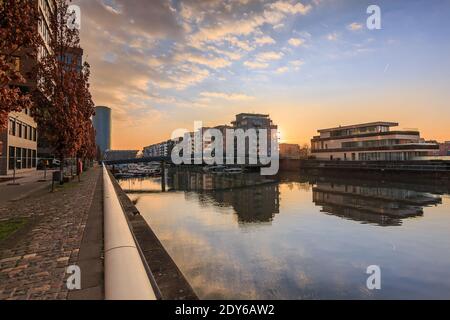 Kanal vom Main in Frankfurt. Wohngebiet am Morgen bei Sonnenaufgang. Wasserfront mit Reflexion. Blauer Himmel und Wolken. Ufer im por Stockfoto