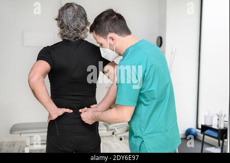 Rückansicht eines Physiotherapeuten, der den Mann auf den Rücken untersucht. Hochwertige Fotos Stockfoto