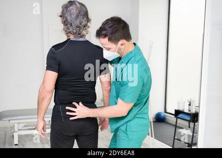 Rückansicht eines Physiotherapeuten, der den Mann auf den Rücken untersucht. Hochwertige Fotos Stockfoto