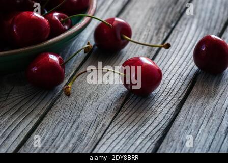 Dunkelrote Kirschen auf grauem Holzhintergrund Stockfoto