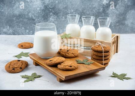 Gläser Milch mit Schokoladenkeksen und Blättern Stockfoto