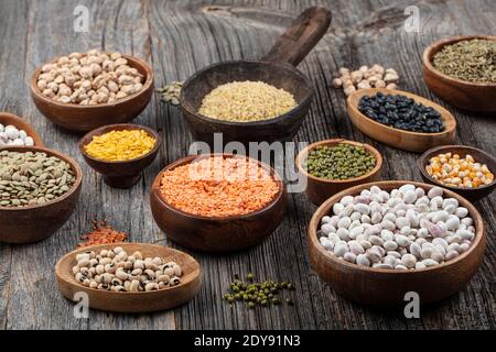 Vegane Proteinquelle.verschiedene Auswahl an Hülsenfrüchten, Linsen, Kichererbsen und Bohnen Sortiment in verschiedenen Schüsseln auf Holztisch. Draufsicht. Stockfoto