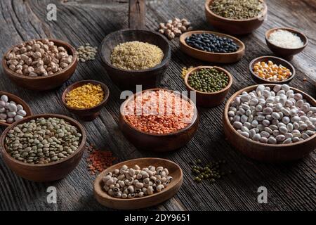 Vegane Proteinquelle.verschiedene Auswahl an Hülsenfrüchten, Linsen, Kichererbsen und Bohnen Sortiment in verschiedenen Schüsseln auf Holztisch. Draufsicht. Stockfoto