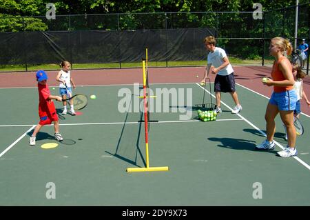 Kleine Kinder, die Tennisunterricht von einer lokalen Gemeinde zur Verfügung gestellt Damit Kinder das Tennisspiel lernen können Stockfoto