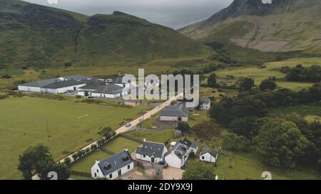 Arran Whiskey Distillery Antenne. Straße in grünen Bergen Tal. Schottisches Dorf mit Hütten, Häusern, Lager. Ländliche Landschaft der Landstraße im Sommer. Kinofilm Schottland Alkohol industy Schuss Stockfoto