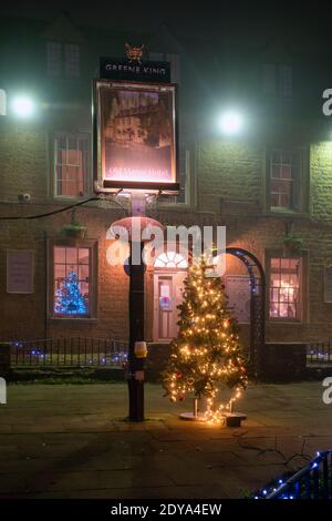 Weihnachtsbaum und Lichter im Nebel vor dem alten Mähne Hotel in der Nacht. Bourton on the Water, Cotswolds, Gloucestershire, England Stockfoto