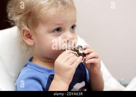 Nachdenkliche Kind essen Pfannkuchen im Hochstuhl zu Hause Stockfoto