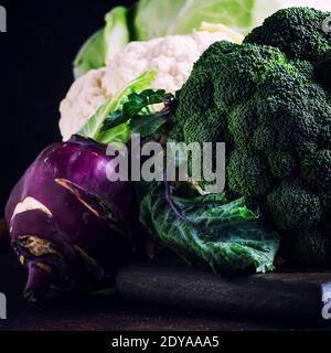 Verschiedene Arten von Kohl wie Weißkohl, Blumenkohl, Brokkoli, Kohlrabi auf dunklem Tisch, Herbsternte, selektiver Fokus Stockfoto