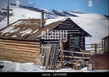 Eine alte Gehöft-Blockhütte im Schnee, auf einer Rinderfarm in Porter's Corner, am Fuße der John Long Mountains, südwestlich von Philipsburg, in Stockfoto