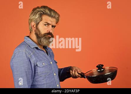 Wer kümmert sich um Ernährung. Kulinarisch und Küche. Küchenutensilien. Gesundes Essen Kochen. Kochen schmackhafte Gericht. Bärtige Mann halten Bratpfanne. Kochen im Topf. Für die Zubereitung von Speisen. Bärtiger Mann, der in der Küche kocht. Stockfoto