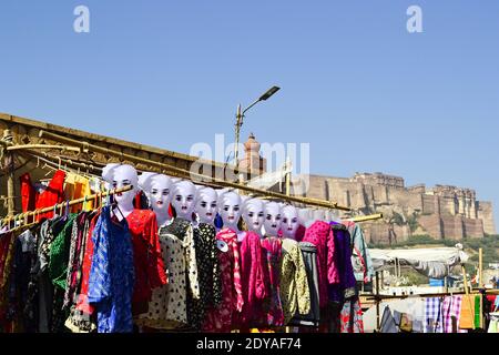 Blick von der Altstadt auf das Mehrangarh Fort. Frau Schaufensterpuppen mit indischem Tuch auf dem Straßenmarkt im Vordergrund. Jodhpur, Rajasthan, Indien. Stockfoto