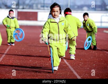 Changxing, Chinas Provinz Zhejiang. Dezember 2020. Kinder spielen ein "Eisen-Ring-Rollen"-Spiel im Hongqiao Zentralkindergarten im Bezirk Changxing der Stadt Huzhou, ostchinesische Provinz Zhejiang, 25. Dezember 2020. Der Kindergarten veranstaltete verschiedene traditionelle Volksaktivitäten, um das kommende neue Jahr zu feiern. Quelle: Xu Yu/Xinhua/Alamy Live News Stockfoto