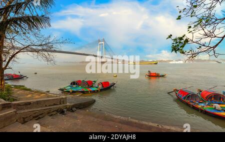 Princep Ghat mit Holzbooten und Blick auf Vidyasagar Setu Kabelbrücke über den Fluss Ganges bei Kalkutta Indien Stockfoto