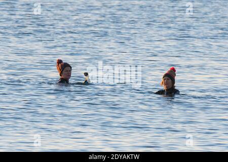 Mudeford, Dorset, Großbritannien. Dezember 2020. Wetter in Großbritannien. Schwimmer genießen ein Bad im Meer am Avon Beach in Mudeford in Dorset an einem kalten, klaren sonnigen Morgen am Weihnachtstag. Bild: Graham Hunt/Alamy Live News Stockfoto