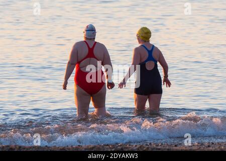 Mudeford, Dorset, Großbritannien. Dezember 2020. Wetter in Großbritannien. Schwimmer gehen für ein Bad im Meer am Avon Beach in Mudeford in Dorset an einem kalten, klaren sonnigen Morgen am Weihnachtstag. Bild: Graham Hunt/Alamy Live News Stockfoto