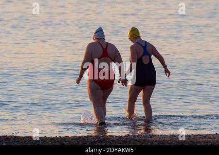 Mudeford, Dorset, Großbritannien. Dezember 2020. Wetter in Großbritannien. Schwimmer gehen für ein Bad im Meer am Avon Beach in Mudeford in Dorset an einem kalten, klaren sonnigen Morgen am Weihnachtstag. Bild: Graham Hunt/Alamy Live News Stockfoto