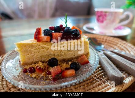 Käsekuchen mit vielen frischen Erdbeeren, Himbeeren und Heidelbeeren in einem Café im Vintage-Stil gekrönt. Stockfoto